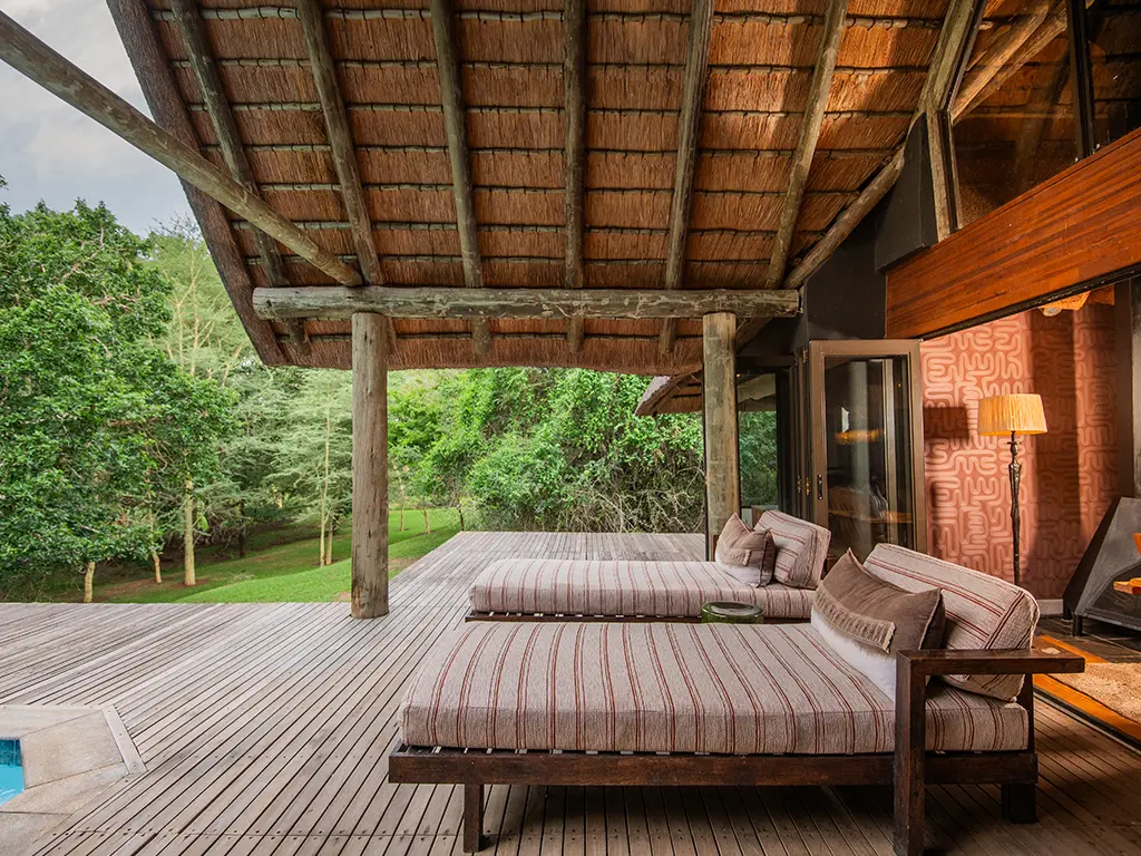 An exterior view of the spacious wooden sun deck outside the luxury safari Homestead at Rhino River Lodge, featuring lounge seating next to a private swimming pool overlooking the green bushveld lawns.